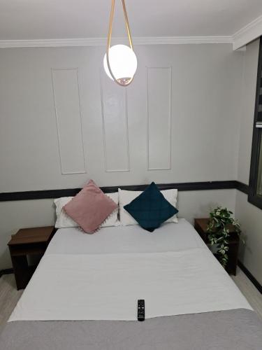 a bedroom with a white bed with pillows and a light at Hotel Asturias in Viña del Mar
