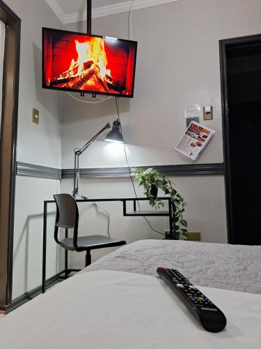 a bedroom with a tv and a bed with a remote control at Hotel Asturias in Viña del Mar