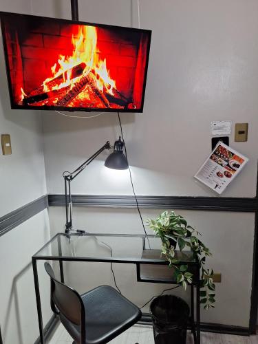a desk with a lamp and a fire on the wall at Hotel Asturias in Viña del Mar