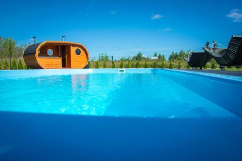 a swimming pool with a tree house in the background at Kika House in Pasym