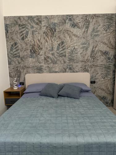 a bed with two pillows in front of a wall at Vico Terzo Guest House in Deliceto