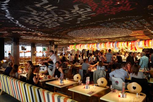 a crowd of people sitting at tables in a restaurant at Mama Shelter Bordeaux Centre in Bordeaux