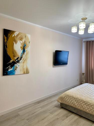 a bedroom with a bed and a tv on a wall at River Apartments in Vinnytsya