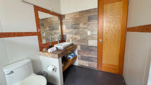 a bathroom with a toilet and a wooden door at Finca Catalina Hotel Boutique in Tepoztlán