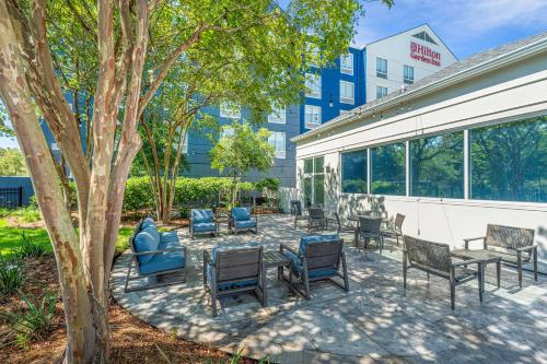 a patio with chairs and tables next to a building at Hilton Garden Inn Charleston Airport in Charleston