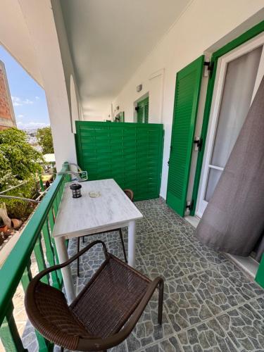 a table and chair on a balcony with green doors at Paradise Garden Paros in Piso Livadi