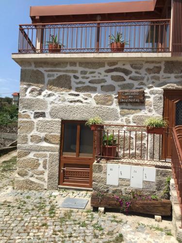 a stone building with potted plants on a balcony at Cantinho das Tecedeiras in Mondim de Basto