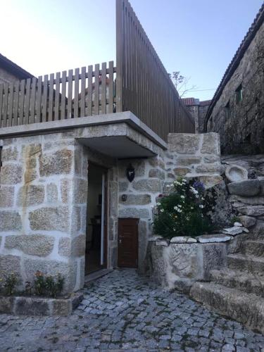 a stone building with a wooden gate and stairs at Cantinho das Tecedeiras in Mondim de Basto