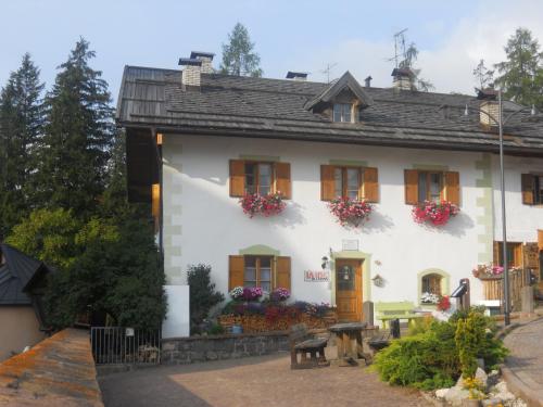 a white house with flowers on the windows at Achillea Bed & Breakfast in Vigo di Fassa