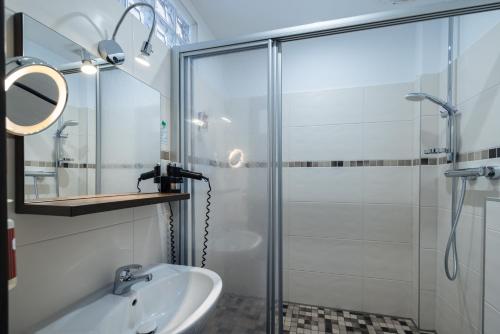 a bathroom with a glass shower and a sink at home Hotel in Wilhelmshaven