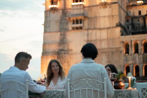 a group of people sitting at a table in front of a tower at The Castle View Homestay in Būndi