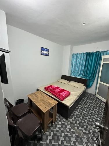 a small room with a bed and a table and chairs at Pearl Homestay Mussoorie in Mussoorie