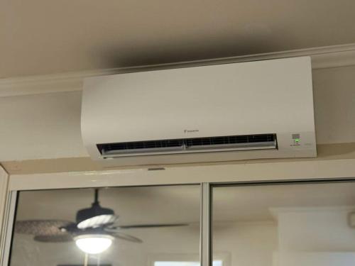 a white air conditioner on a ceiling above a window at Kamaole Beach Club B107 in Kihei
