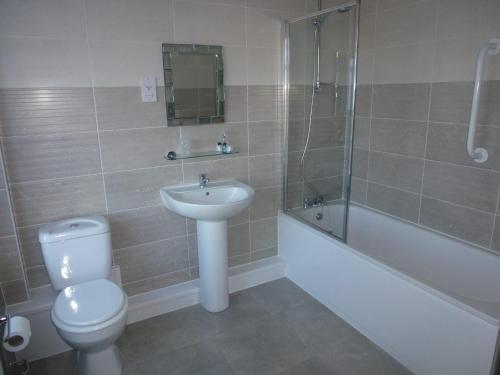 a bathroom with a toilet and a sink and a bath tub at Orrell Park Hotel in Liverpool