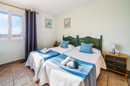 Villa Angela Flores by Villa Plus في تيولادا: سريرين في غرفة بها نافذة