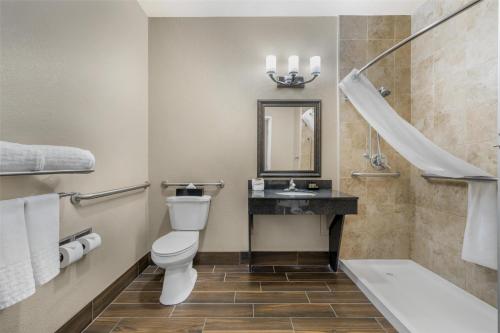 a bathroom with a toilet and a sink and a tub at Best Western Plus Winslow Inn in Winslow