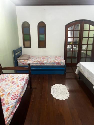 a room with two beds and a wooden floor at Rico Hostel in Cabo Frio