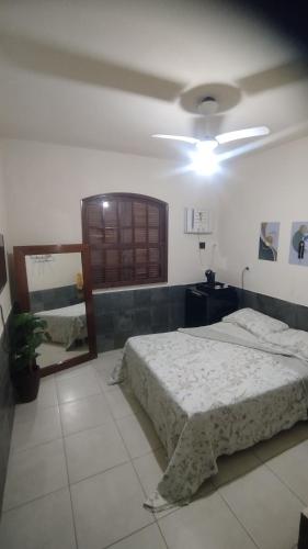 1 dormitorio con cama y espejo. en Hospedaria Clã do Cla, en Arraial do Cabo
