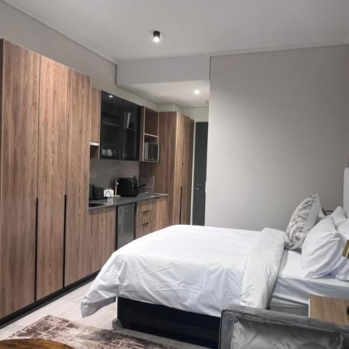 a bedroom with a bed and a kitchen at 423 Menlyn maine Apartment in Pretoria