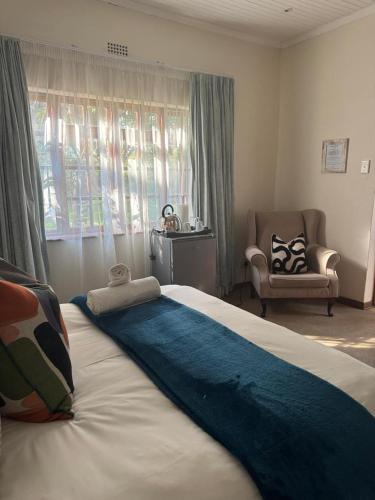 a bedroom with a large bed with a chair and a window at Rivonia Garden Suites in Johannesburg