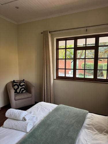 a bedroom with a bed and a chair and a window at Rivonia Garden Suites in Johannesburg