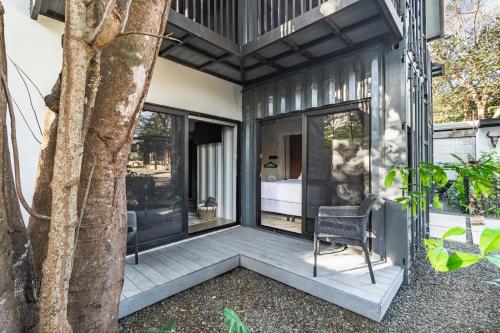 a home with a porch with a tree at Z102 Studios, 4 Industrial Beach Condos w Pool! in Playa Flamingo