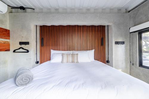 a bedroom with a large white bed with a wooden headboard at Z102 Studios, 4 Industrial Beach Condos w Pool! in Playa Flamingo