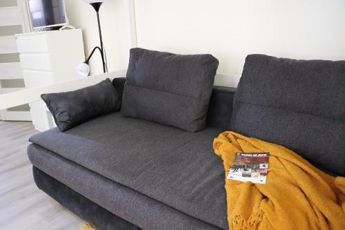 a grey couch with a blanket on top of it at Apartmán Denisa in Rokytnice nad Jizerou