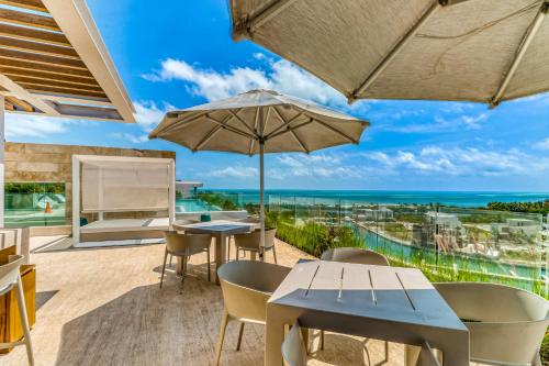 Un patio con mesas y sillas y una sombrilla. en Riva Puerto Cancun # 207, Halibut, en Cancún
