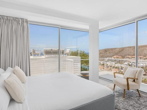 Un dormitorio con una cama blanca y una ventana grande. en Villa Serena Find Luxury & Serenity in Tenerife, en Palm-mar