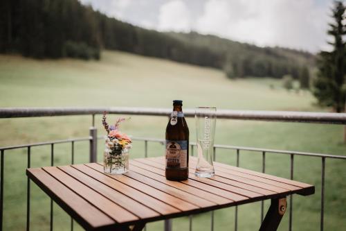 a bottle of beer and two glasses sitting on a wooden table at Luxuriöse Schwarzwald Loft Heustock mit Sauna und Whirlpool am Griesbachhof in Titisee-Neustadt