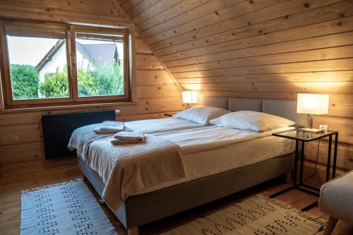 a bed in a wooden room with a window at Domek 'Słoneczna 2' z RUSKĄ BANIĄ in Kluszkowce