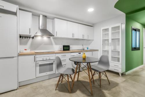 a kitchen with white cabinets and a table and chairs at Living Central Stay Bejeque in Vecindario