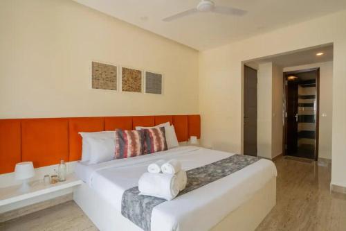 a bedroom with a large white bed with two towels at Lavish Apartments with Pool Candolim Luxfort in Candolim