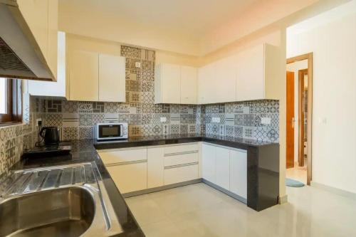 a kitchen with white cabinets and a sink at Lavish Apartments with Pool Candolim Luxfort in Candolim