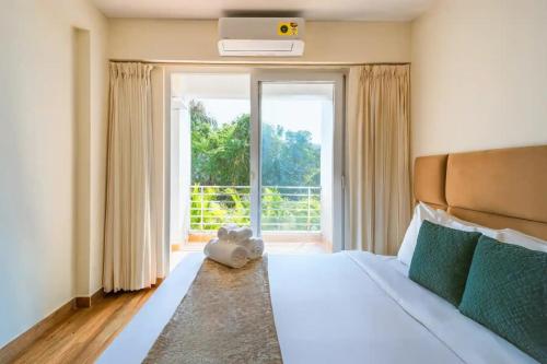 a bedroom with a large bed and a large window at Lavish Apartments with Pool Candolim Luxfort in Candolim