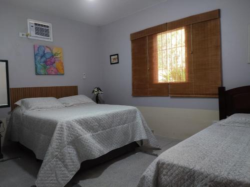 a bedroom with two beds and a window at Casa na Boraceia, 100 M praia c roupas cama e banho in São Sebastião