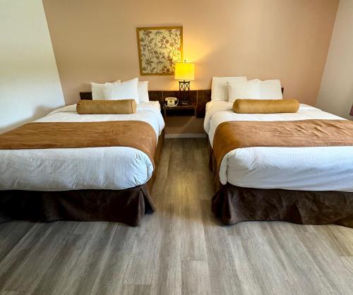 a hotel room with two beds and a lamp at Swiss Village Inn in Golden