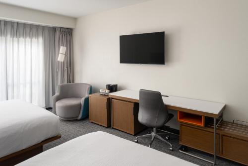 a hotel room with a desk and a tv on the wall at Courtyard Brunswick in Brunswick