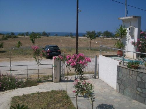 a car parked in a driveway with a fence and flowers at Paschalia sea view studios in Psakoudia