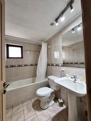 a bathroom with a tub and a toilet and a sink at Torremolinos departamentos in Temuco