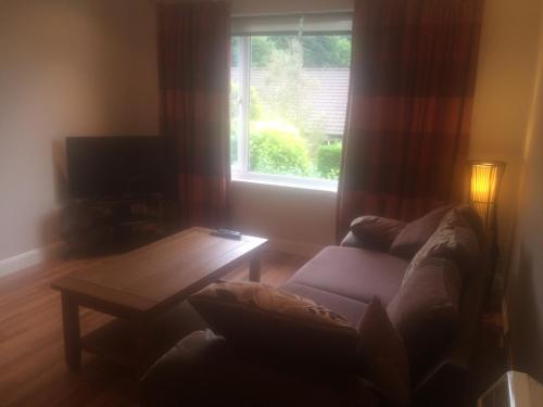 sala de estar con sofá, mesa y ventana en An Teallach en Oban