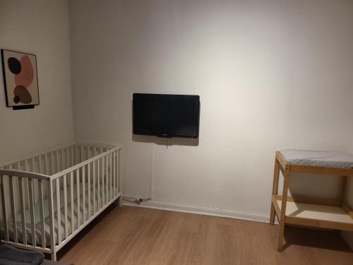 a room with a crib and a flat screen tv on the wall at La Parenthèse Auvergnate, F3 2 Chambres Clermont-Ferrand in Clermont-Ferrand