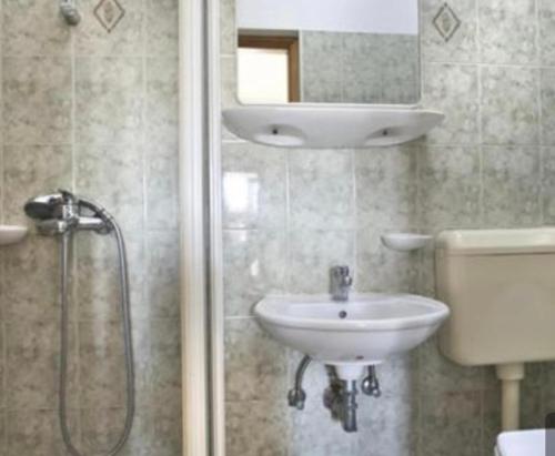 a bathroom with a sink and a shower with a mirror at Relax Apartments Grazia in Funtana