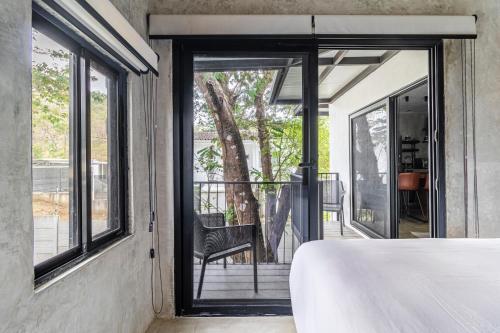 a bedroom with a door open to a balcony at Z102 Studios, 4 Industrial Beach Condos w Pool! in Playa Flamingo