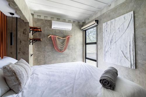 a bedroom with a white bed and a window at Z102 Studios, 4 Industrial Beach Condos w Pool! in Playa Flamingo