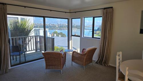 a living room with a table and chairs and a large window at 2 Bedroom home, City and Sea Views in Auckland