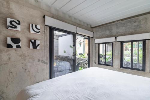 a bedroom with a large white bed and windows at Z102 Studios, 4 Industrial Beach Condos w Pool! in Playa Flamingo