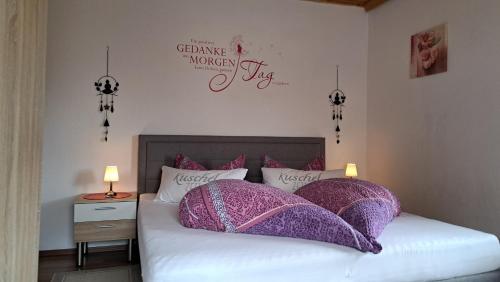 a bedroom with a bed with purple and white pillows at Fewo Steinbeisser in Arrach