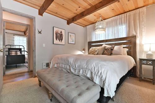 Schlafzimmer mit einem großen Bett mit einer Bank in der Unterkunft Cozy Chic Chalet - Enchanting & Fun Family Retreat - Hot Tub & Fire Pit - Dog Friendly in Dorrington